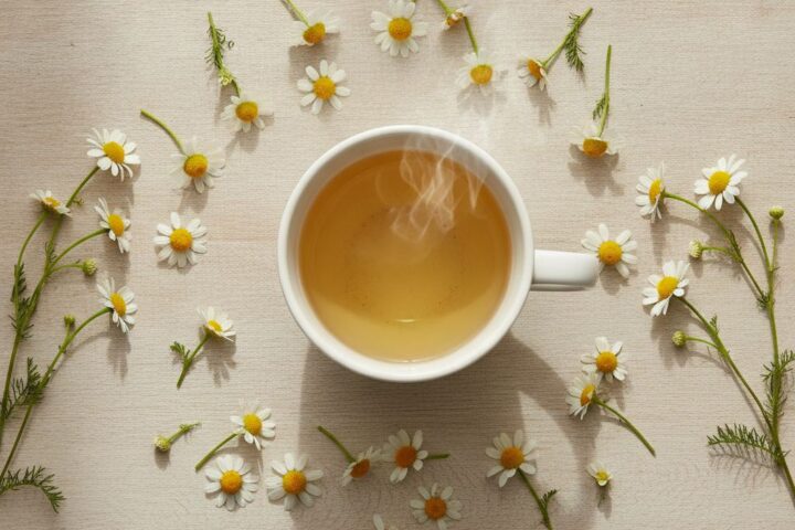 Xícara de chá de camomila com flores frescas sobre mesa clara